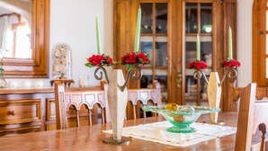 Une table à manger agrémentée de quatre chandeliers, chacun contenant une bougie verte et des fleurs rouges.
