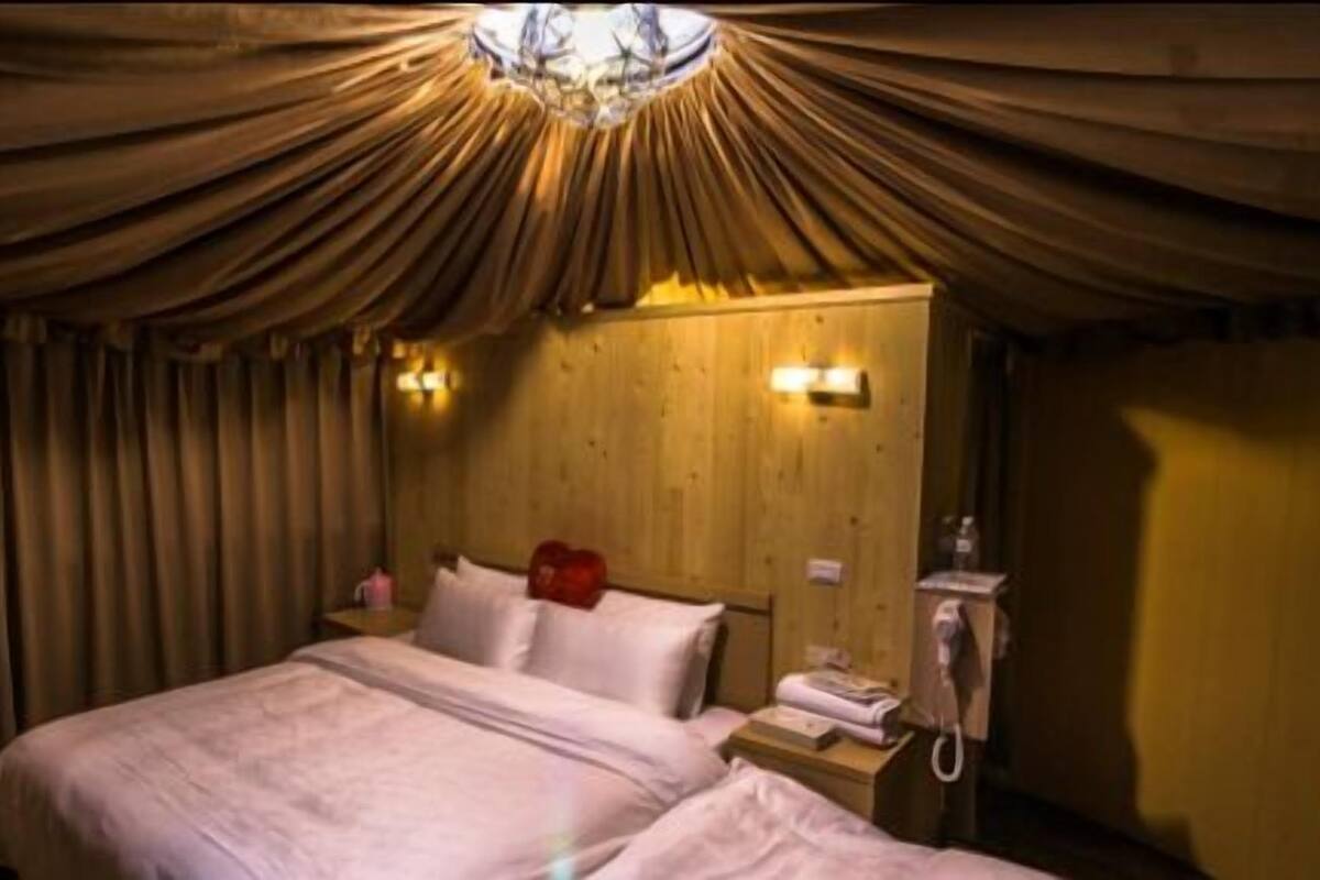 Una habitación con una cama, una mesita de noche, un teléfono y una lámpara de pared.