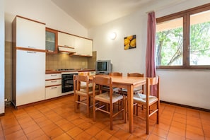 A compact kitchen with white cabinets, a wooden dining table, and chairs.