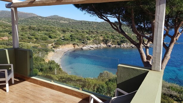 Eine Holz-Pergola mit Blick auf eine Küstenlandschaft, darunter ein Strand und Hügel.