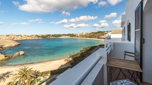 A balcony with a view of a beach and clear blue waters. - Beautiful Apartment with Wi-Fi, Pool, Terrace and Sea View (Arenal d'en Castell)