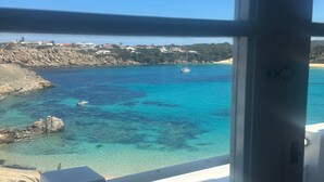 A coastal view from a window, featuring clear turquoise waters, a sandy beach, and buildings in the background. - Beautiful Apartment with Wi-Fi, Pool, Terrace and Sea View (Arenal d'en Castell)