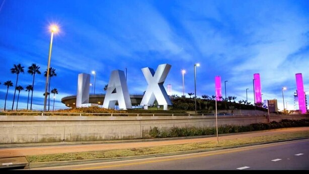 A large 'LAX' sign with a modern design, surrounded by palm trees and street lights. - LAX guest house (Inglewood)
