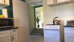 A compact kitchen with white cabinets, a built-in oven, and a countertop with a kettle. - LAX guest house (Inglewood)