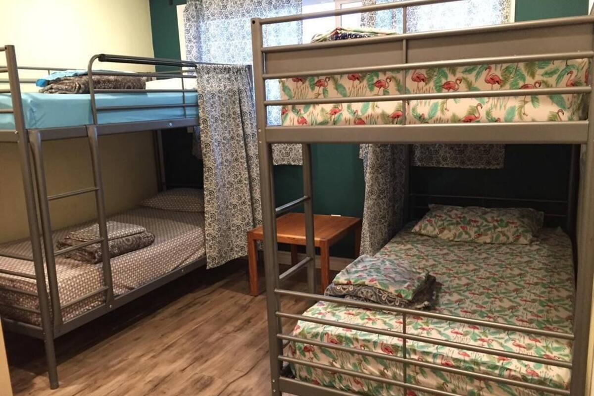Un dormitorio con literas, una mesa de madera y cortinas estampadas.