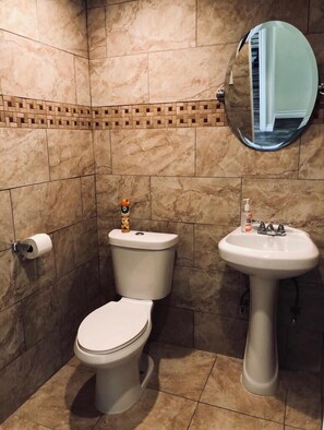 A bathroom with a toilet, sink, and a mirror. - LAX guest house (Inglewood)