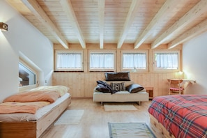 Une chambre avec un lit en mezzanine, un canapé-lit, un plafond en bois et trois fenêtres avec des rideaux.