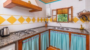 A kitchen with a gas stove, sink, and a window with blinds.