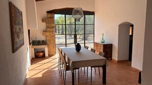 A dining area with a table, chairs, a chandelier, a large window, and a stone wall. - Secluded Villa with Pool, Wi-Fi, Air Conditioning and Terrace; Parking available (Alaró)
