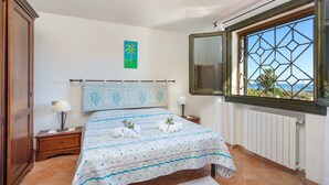 A bedroom with a bed, two bedside tables, a window with a view, and a wall with a painting. - Beautiful Sun House Villa with Sea View, Wi-Fi, Balcony & Terrace (Cannigione)