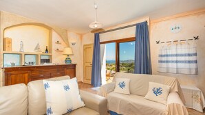 A cozy living room with a sofa, a table, and a view of the outdoors. - Beautiful Sun House Villa with Sea View, Wi-Fi, Balcony & Terrace (Cannigione)