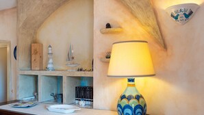 A room with a lamp, bookshelves, decorative items, and a wall-mounted light fixture. - Beautiful Sun House Villa with Sea View, Wi-Fi, Balcony & Terrace (Cannigione)