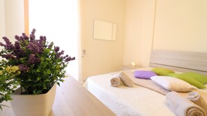 Ein Hotelzimmer mit Bett, einer Zimmerpflanze und einem Nachttisch.