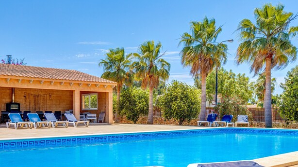 A pool area with lounge chairs, a covered seating area, and palm trees. - Beautiful and Spacious Villa in a Quiet Location with Large Pool, Terrace, Balcony & Garden (Campos)