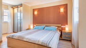 A bedroom with a large bed, two bedside tables, a wooden headboard, and two wall-mounted lights. - Beautiful and Spacious Villa in a Quiet Location with Large Pool, Terrace, Balcony & Garden (Campos)