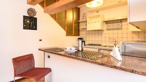 A kitchen with a wooden ceiling, a red woven chair, a coffee maker, and a toaster. - Charming Lake Garda Home - Civic 55 (Toscolano Maderno)