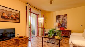 A living room with a TV, a sofa, a coffee table, and a painting on the wall. - Charming Lake Garda Home - Civic 55 (Toscolano Maderno)