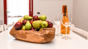 A wooden bowl with fruits and a wine bottle on a table. - Charming Lake Garda Home - Civic 55 (Toscolano Maderno)