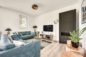 A modern living room with a blue sofa, a coffee table, a TV, and a plant.