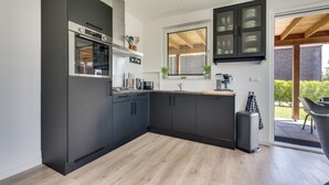 Een moderne keuken met donkere kastjes, een ingebouwde oven en een raam met zonwering.