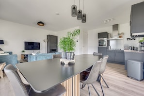 A modern kitchen with a dining area, built-in appliances, and a large potted plant.