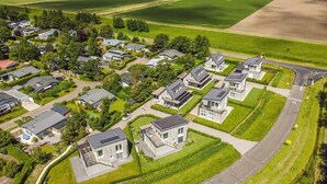 Een luchtbeeld van een woonwijk met moderne huizen, verzorgde gazons en een heldere weg.