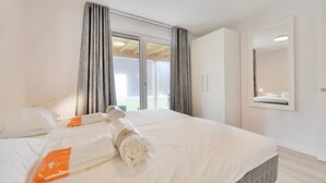 Een hotelkamer met een bed, een groot raam met gordijnen, een kledingkast en een spiegel.