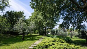 Un jardin avec un sentier en pierre, une végétation luxuriante et des arbres.