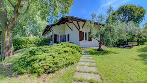 Une maison avec un chemin de pierre menant à l’entrée, entourée d’une végétation luxuriante et d’arbres.