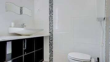 Ein Badezimmer mit einem weißen Waschbecken, schwarzen Schränken, einer weißen Toilette und einer gefliesten Rückwand.