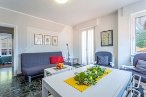 A modern living room with a sofa, a coffee table, and a dining area.