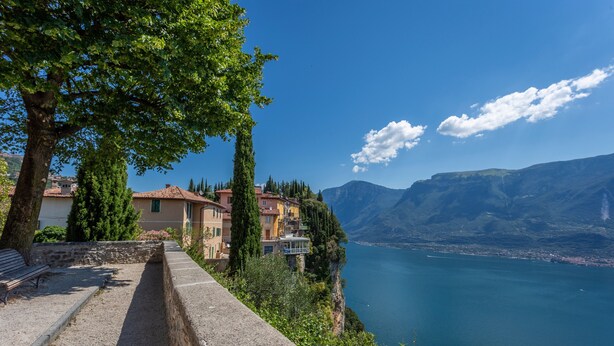 A coastal view with a stone pathway, buildings, and a lake. - Beautiful Nature and Historic Center – Liver 203 (Pieve di Tremosine sul Garda Brescia)