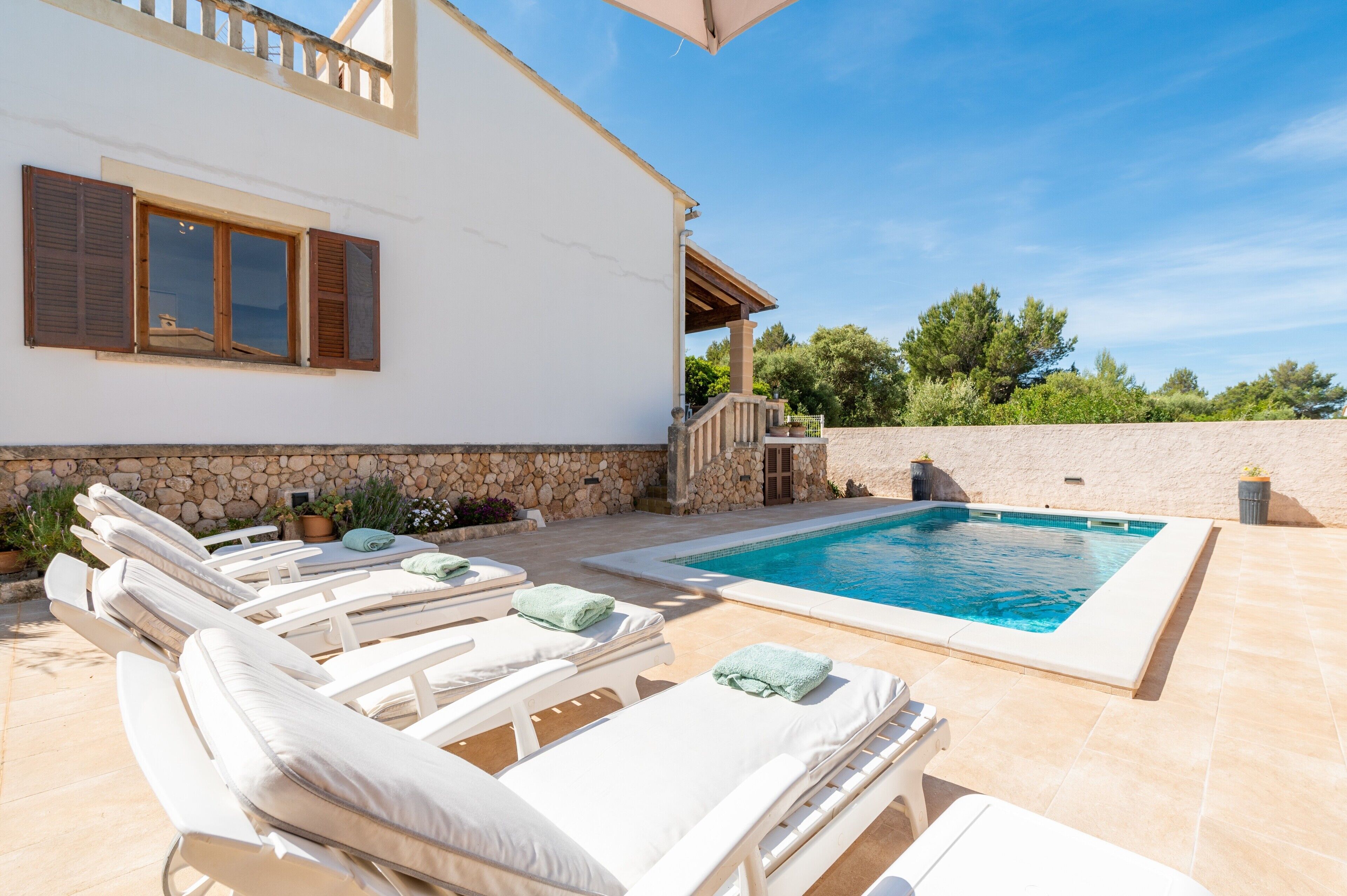 Un espace aménagé au bord de la piscine, avec des chaises longues et une piscine.