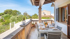 An outdoor dining area with a table set for two, a potted plant, and a view of the surrounding landscape. - Air-Conditioned Holiday Home with Pool, Garden, Terrace & Wi-Fi (Colonia de Sant Pere)
