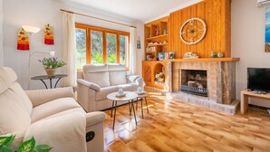A living room with a fireplace, sofa, and TV. - Air-Conditioned Holiday Home with Pool, Garden, Terrace & Wi-Fi (Colonia de Sant Pere)