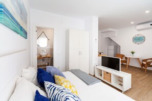 Une chambre moderne avec un lit, une télévision et un coin repas comprenant des chaises et une table.