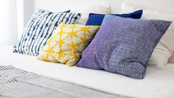 Un lit avec plusieurs oreillers, une tête de lit blanche et une couverture à rayures.