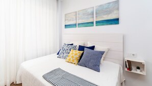 Une chambre à coucher bien rangée, avec un lit, des oreillers, une table de chevet et une étagère fixée au mur.