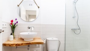 Une salle de bain avec un meuble-lavabo en bois, un lavabo blanc, un miroir, des toilettes et une douche.