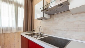 A kitchen with a white countertop, stainless steel sink, red cabinets, and a window with curtains. - With panoramic views in the hills – Apartment GeoResort A2 (Tremosine sul Garda)