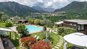 A pool with a view of mountains, a patio area, and a garden. - With panoramic views in the hills – Apartment GeoResort A2 (Tremosine sul Garda)