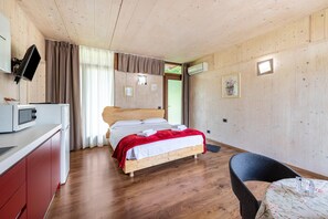 Un dormitorio con cama, escritorio, silla, televisor y aire acondicionado.