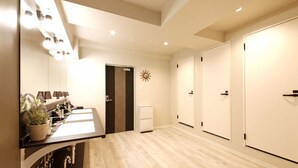A hotel room with a wooden floor, a sink, a mirror, a plant, and a wardrobe. - Lestel Maru - Hostel (Sapporo)