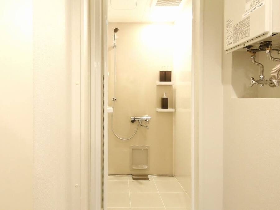 A narrow bathroom with a shower, a toilet, and a sink.