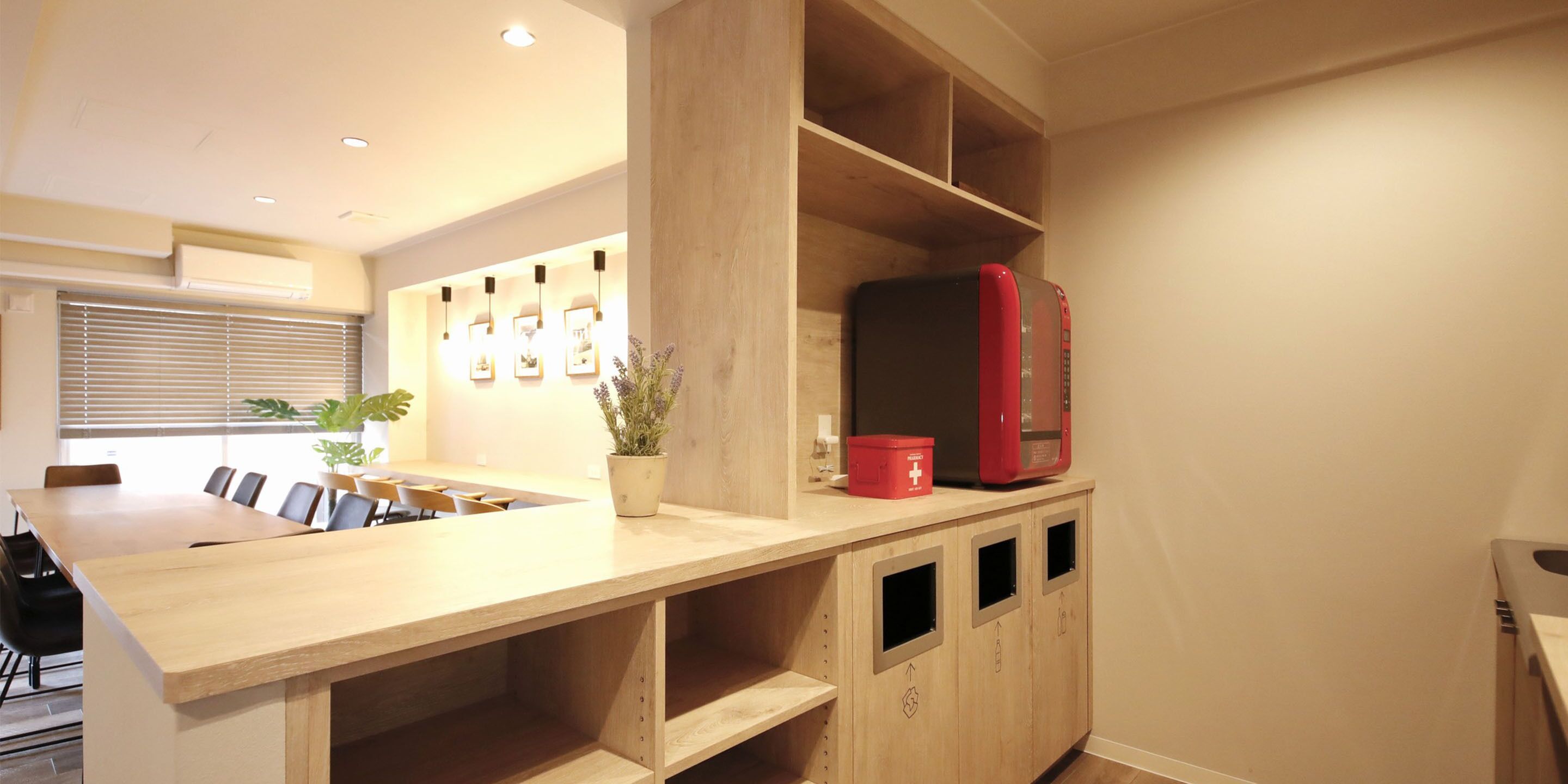 A modern kitchen with a wooden countertop, a red refrigerator, and a potted plant.