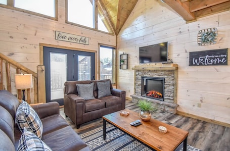 A cozy living room with a fireplace, leather couches, and a wooden interior.