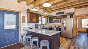 Una cocina moderna con una isla central, taburetes de bar, un refrigerador y un letrero que dice "FRESH PRODUCE".