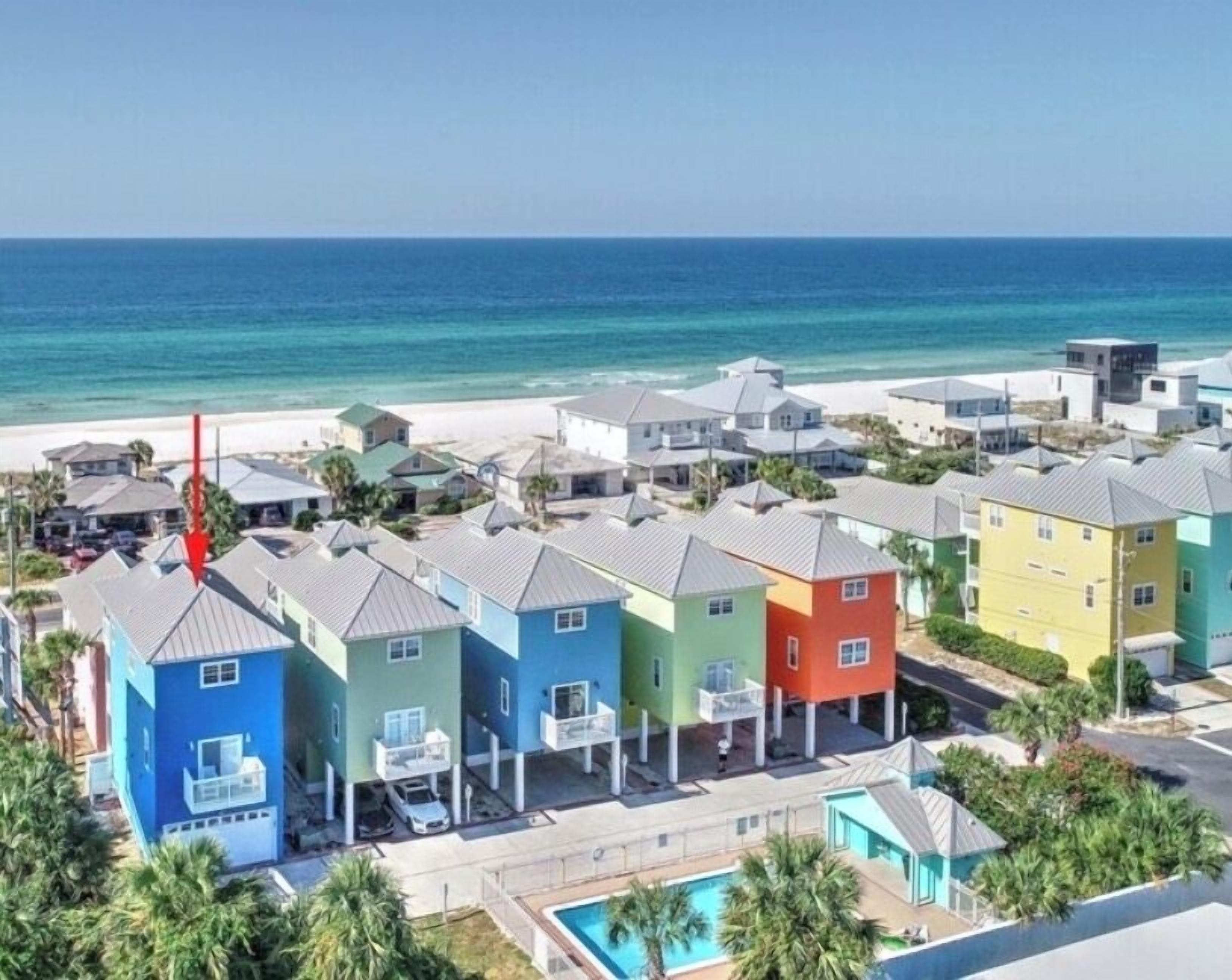 Zona residencial costera con casas coloridas, una playa y una vista despejada del océano.