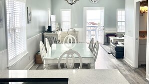 Una cocina amplia con una isla grande, un comedor con mesa de vidrio y una araña.