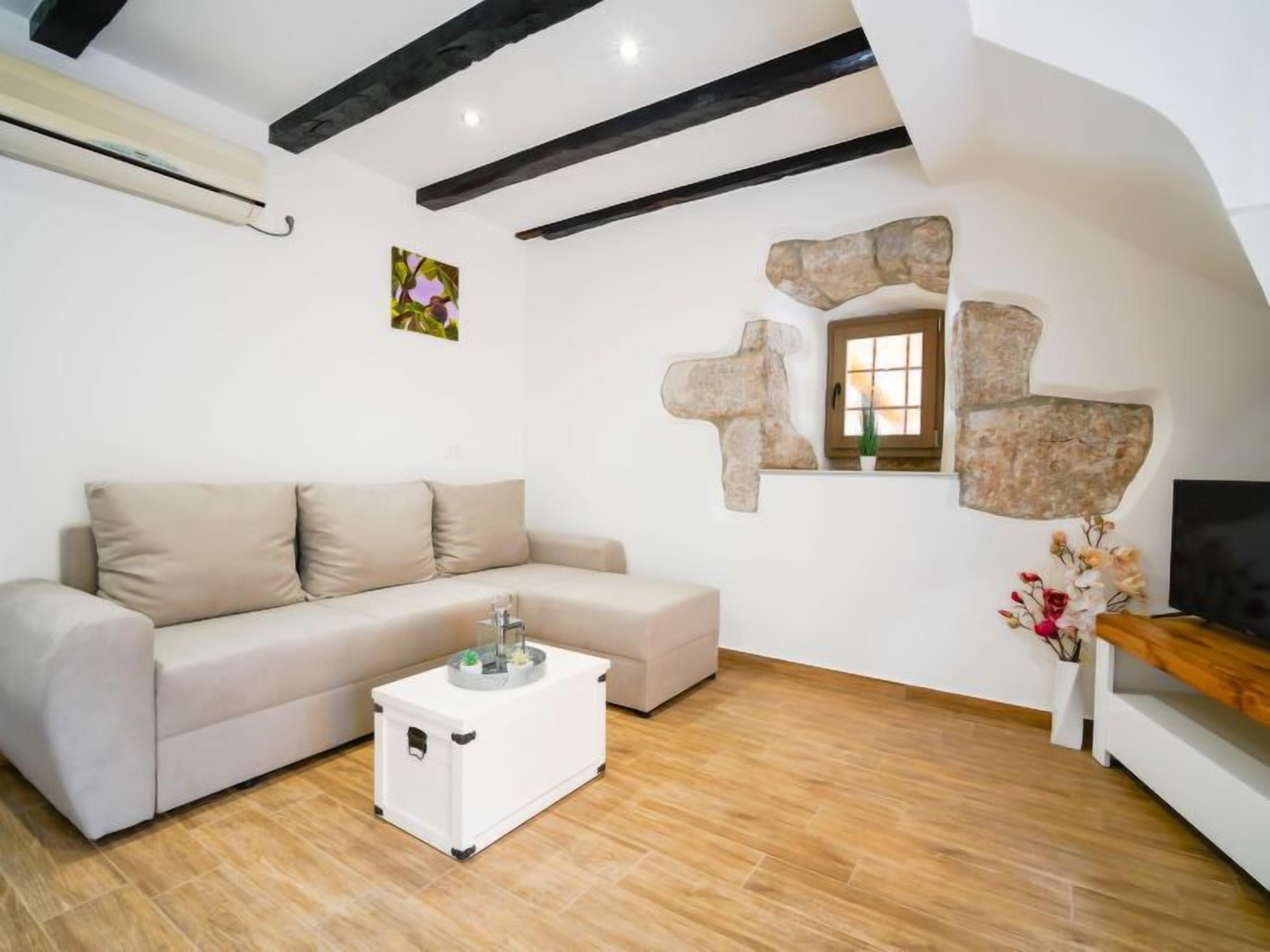 Un soggiorno moderno con un divano beige, un tavolino bianco e una parete in pietra.
